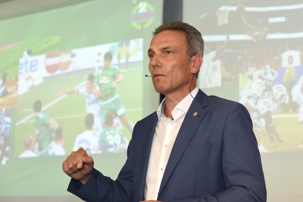 Michael Krammer während seinem Vortrag mit einem Bild eines SK Rapid Spiels im Hintergrund