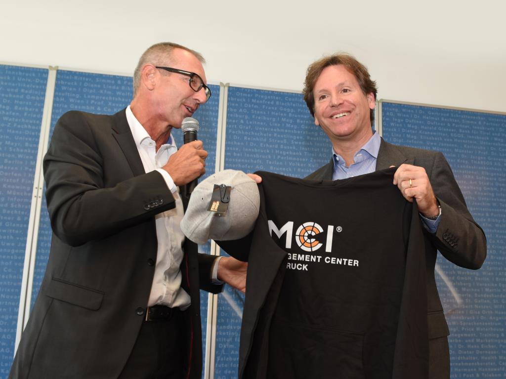 Prof. Dr. Andreas Altmann gives Trevor D. Traina a MCI hoody