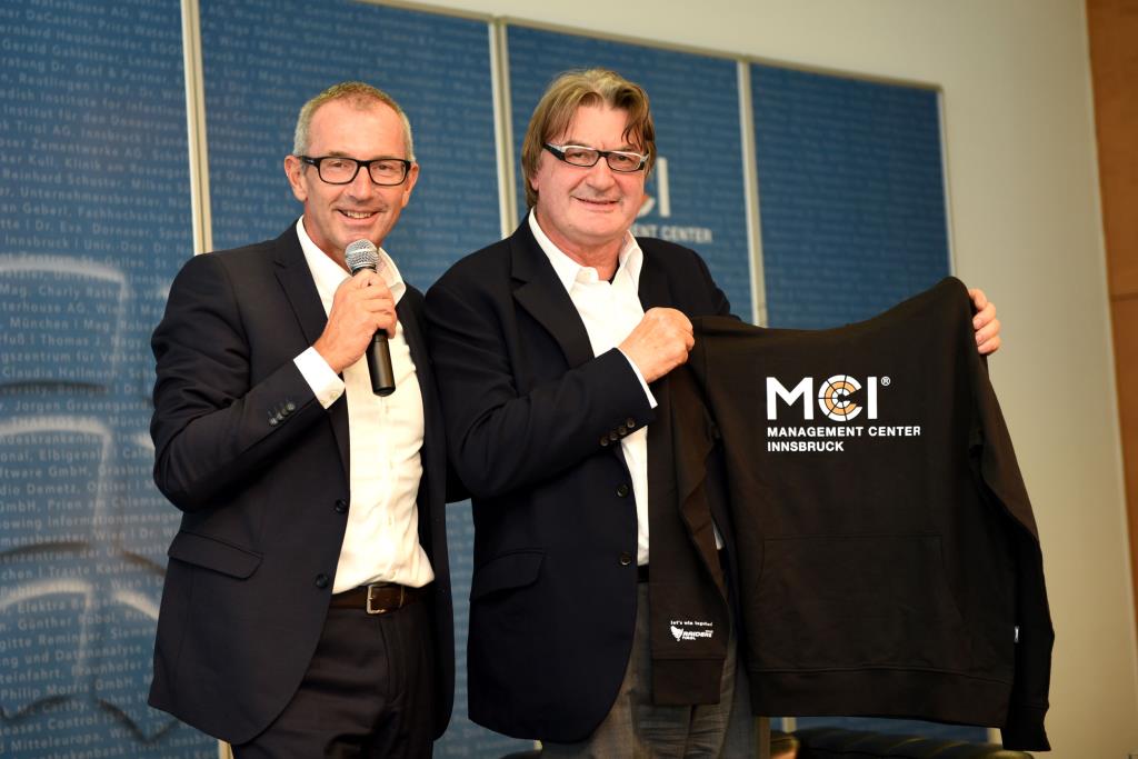 Prof. Dr. Andreas Altman gives Mario Moretti-Polegato a MCI hoody