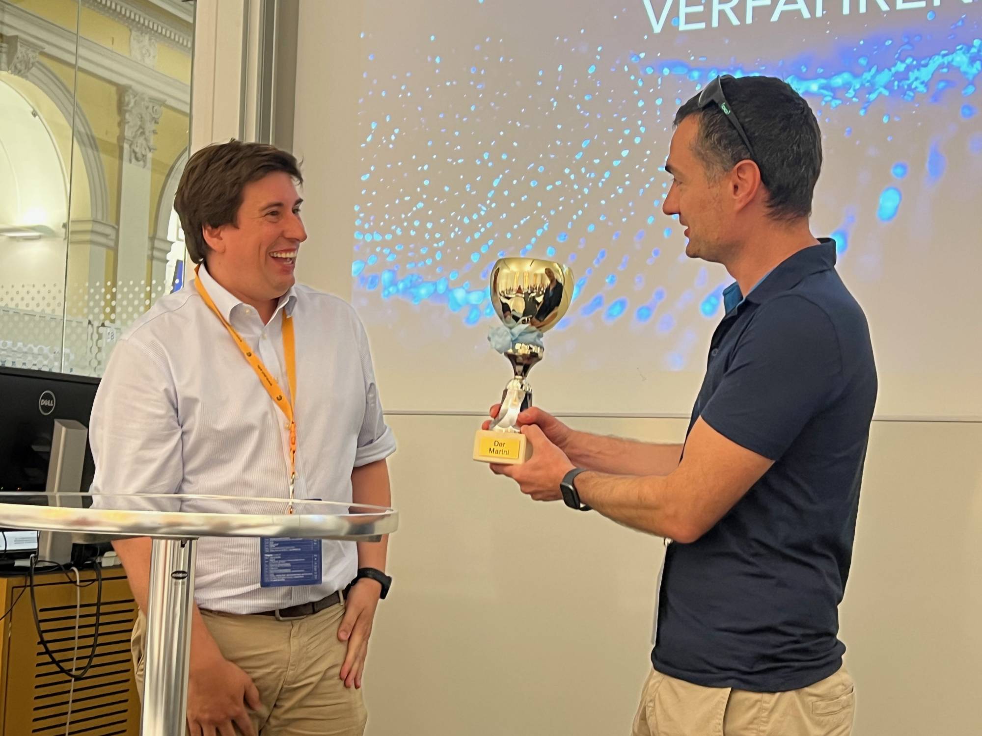<p>Martin Pillei übergibt die Trophäe des Symposiums an Simon Schneiderbauer von der Johannes Kepler Universität Linz © MCI/Barbara Koller</p>