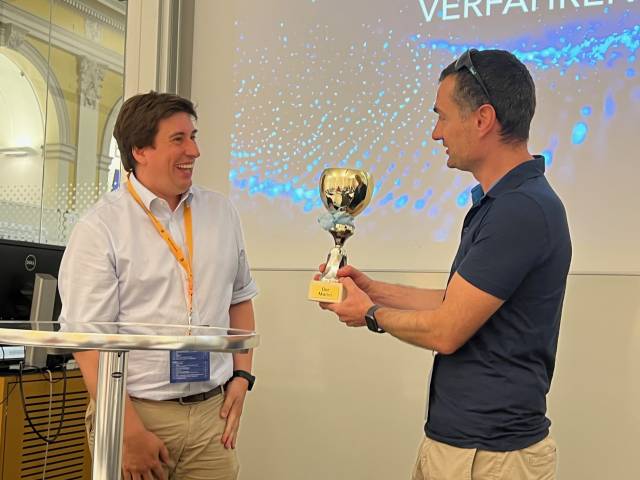 <p>Martin Pillei übergibt die Trophäe des Symposiums an Simon Schneiderbauer von der Johannes Kepler Universität Linz © MCI/Barbara Koller</p>