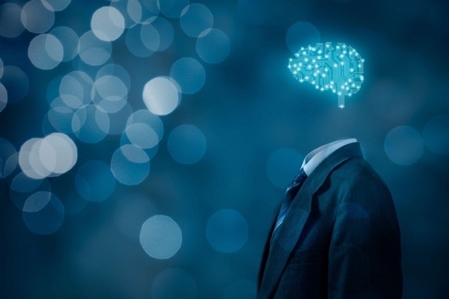 Künstliche Intelligenz dargestellt in Anzug vor blauem Hintergrund ohne menschlichen Körper aber mit Computer Gehirn